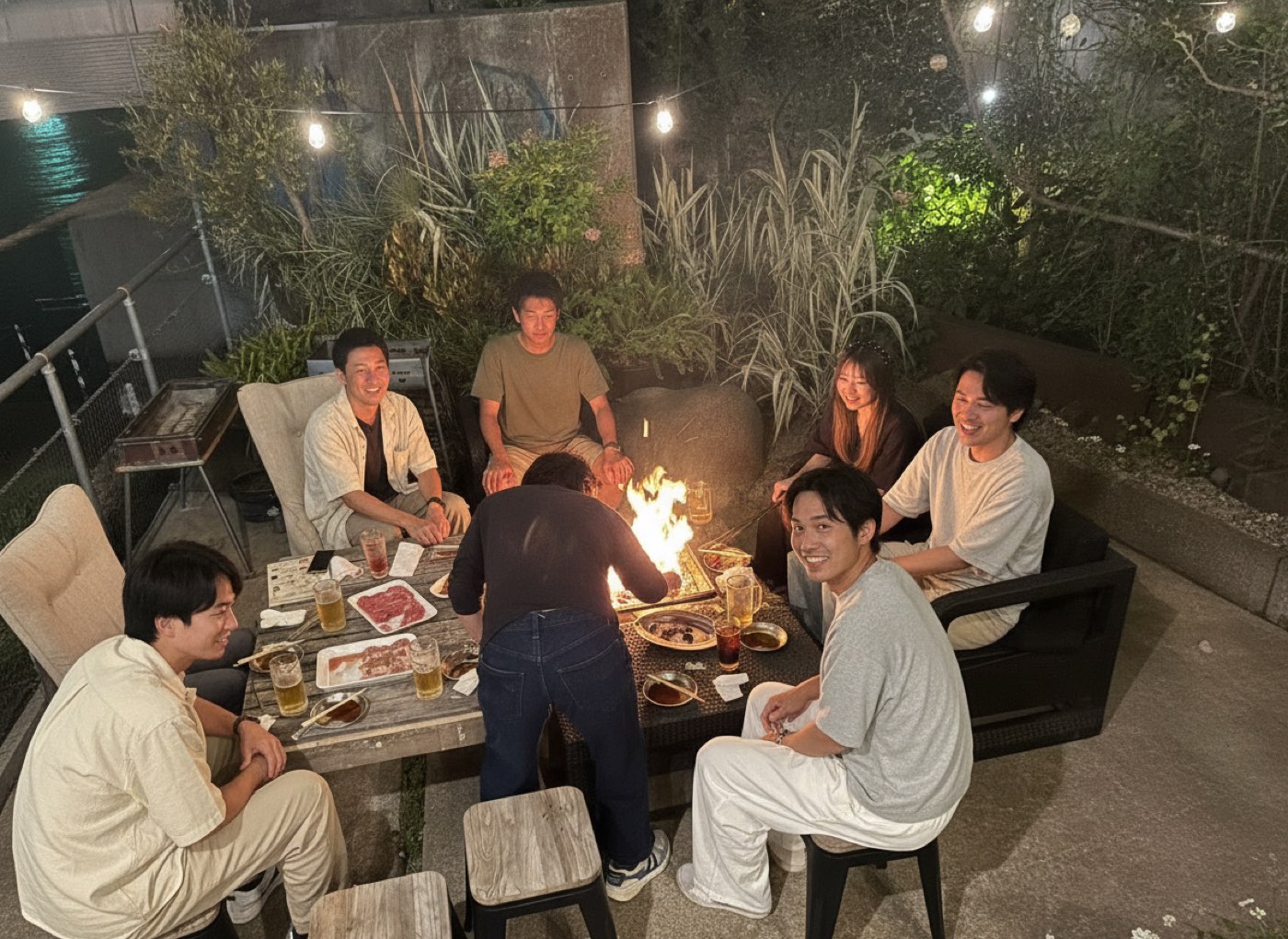 夜のテラス席。照明の下でグリルを囲むお客さま